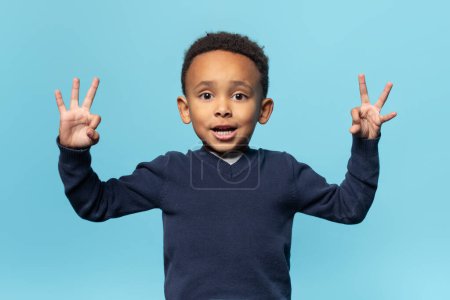 Photo for Cute african american boy showing ok gesture with both hands, posing isolated on blue background, studio shot. Kids education, positive lifestyle, excellent recommendations - Royalty Free Image