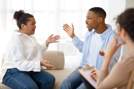 Photo for Emotional furious young mixed race couple figthing at therapy session at family counselor office, hispanic obese woman and black guy yelling and gesturing in front of female psychologist - Royalty Free Image