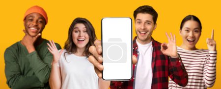 Photo for Smiling multiethnic people show smartphone with empty screen make ok hand gesture isolated on yellow studio background, panorama. Emotion from win, recommendation of website, app, ad and offer - Royalty Free Image