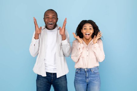 Photo for Human emotions concept. Surprised black spouses spreading hands and exclaiming, looking at camera with excitement, standing on blue studio background - Royalty Free Image
