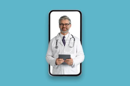 Telemedicine, appointment with doc online. Smiling friendly handsome grey-haired middle aged doctor with digital pad and stethoscope at huge smartphone screen, isolated on blue background, collage
