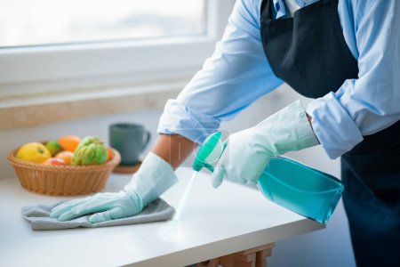 Photo for Unrecognizable tidy african american woman in workwear maid cleaning kitchen, female hands using detergent spray and duster cloth, cropped. House-keeping service, professional cleaning - Royalty Free Image