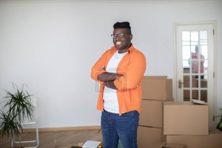 Photo for Smiling Black Man Posing In Room With Cardboard Boxes On Moving Day, Confident African American Male Standing With Folded Arms And Looking At Camera, Celebrating Relocation To New Home, Copy Space - Royalty Free Image