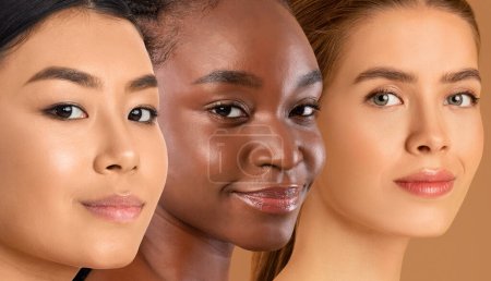 Téléchargez les photos : Visages souriants de dames multiraciales posant sur fond studio beige, trois jeunes femmes multéthniques au maquillage nu montrant une belle peau saine, souriant à la caméra, collage pour le concept de soins de la peau - en image libre de droit