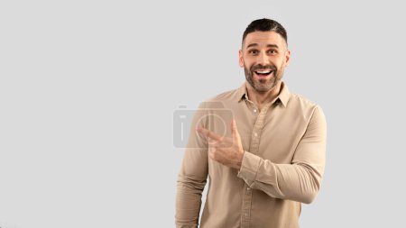 Photo for Cool special offer. Portrait of excited middle aged man pointing finger aside at copy space and looking at camera with excitement, standing over grey studio background, banner panorama - Royalty Free Image