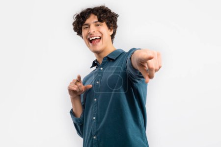 Photo for Hey You. Excited Curly Young Male Pointing Fingers Looking At Camera Choosing You Standing Posing Over White Background In Studio. Youre My Choice Concept. Selective Focus - Royalty Free Image