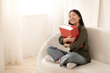 Photo for Overjoyed emotional young asian woman customer receive good parcel cardboard shoe box at home satisfied with great purchase, happy lady consumer hugging package postal shipping delivery, copy space - Royalty Free Image