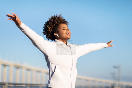 Photo for Freedom Concept. Young Sporty Black Woman Closing Eyes And Spreading Arms Outdoors, Relaxed African American Female In Sportswear Breathing Fresh Air And Smiling While Training Outside On Sunny Day - Royalty Free Image