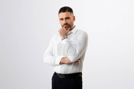 Photo for Pensive businessman touching chin and looking at camera, male entrepreneur thinking about business offer or new startup while standing on grey background - Royalty Free Image