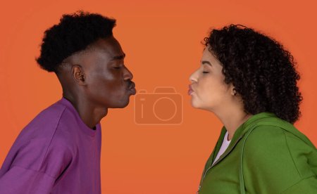 Closeup studio photo of youg loving interracial couple african american guy and hispanic plus size woman kissing on red background, copy space between their lips. Love, affection concept