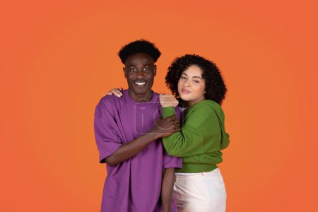 Photo for Loving beautiful young mixed race couple, embracing, smiling at camera, millennial black guy and chubby hispanic curly woman posing on colorful studio background together, showing affection - Royalty Free Image