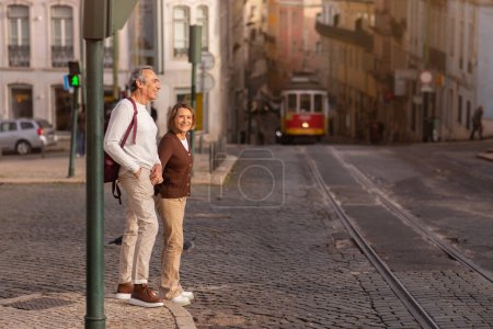 Téléchargez les photos : Épouses mûres gaies debout dehors marchant dans la ville de Lisbonne, traversant une rue voyageant profiter des vacances au Portugal. Concept de voyage et de transport. Prise de vue complète - en image libre de droit