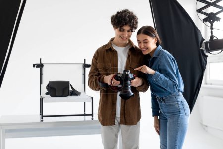 Photo for Team of professional photographer and his female assistant checking the pictures on photocamera while doing content photoshoot for modern bags - Royalty Free Image