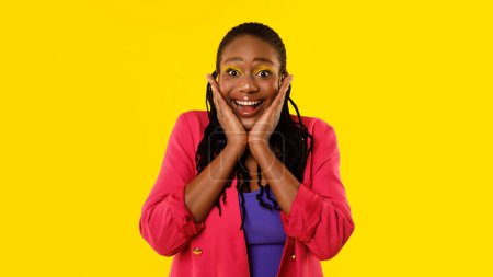 Téléchargez les photos : Omg. Dame afro-américaine émotionnelle avec un maquillage lumineux criant exprimant l'excitation Posant le visage touchant debout sur fond jaune, regardant la caméra. Panorama, Prise de vue studio - en image libre de droit