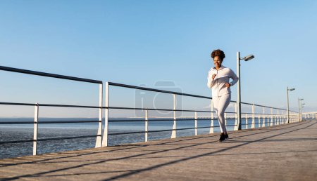 Photo for Motivated Black Female Jogger Running Outdoors On Wooden Pier Near Sea, Happy Young African American Woman In Sportswear Jogging Outside, Enjoying Outdoor Trainings, Panorama With Copy Space - Royalty Free Image