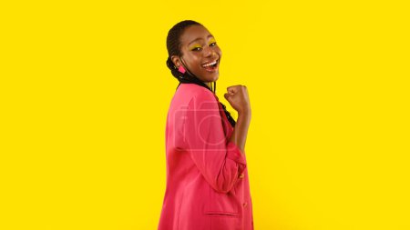 Téléchargez les photos : Femme afro-américaine positive Gesturing Oui regardant la caméra debout en studio sur fond jaune. Dame avec le maquillage lumineux Célébrant la grande chance exprimant la joie. Panorama - en image libre de droit