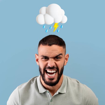 Téléchargez les photos : Angry millennial arabe gars crier avec la bouche ouverte avec un nuage abstrait de foudre et signe de pluie au-dessus de la tête isolé sur fond bleu studio. Stress, mauvaise humeur, émotion humaine négative - en image libre de droit