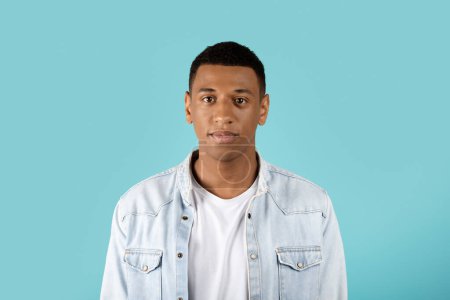 Photo for Portrait of serious calm sad millennial black guy in casual looking at camera isolated on blue studio background, copy space. Human emotions, facial expression, ad and offer - Royalty Free Image