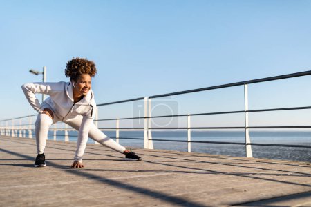 Photo for Sporty Young Black Woman Exercising On Wooden Pier Near Sea, Motivated African American Female In Activewear Stretching Leg Mucles, Athletic Lady Warming Up Before Jogging Outside, Copy Space - Royalty Free Image