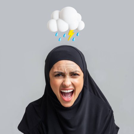 Téléchargez les photos : En colère excité jeune dame islamique dans le hijab paniquer, crier bouche avec un nuage abstrait de foudre et signe de pluie au-dessus de la tête sur fond gris. Problèmes, violence domestique, émotion négative - en image libre de droit