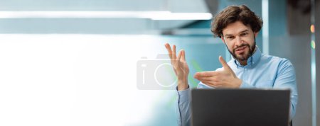 Photo for Happy european adult businessman looks at laptop, gesturing, has video call with client in office interior, empty space. Meeting remotely, business at workplace, social distance and communication - Royalty Free Image