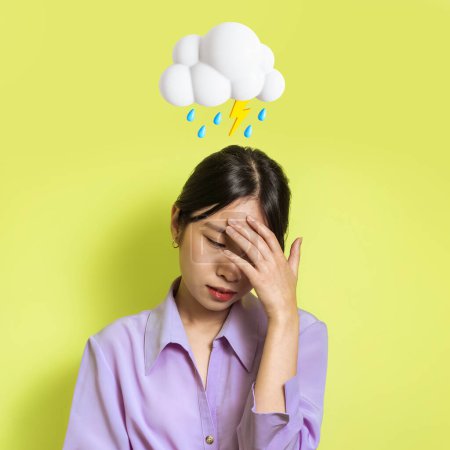 Photo for Sad despaired young asian woman suffering from stress with abstract cloud of lightning and rain sign above head on green studio background. Bad mood, reaction on news, negative, human emotion - Royalty Free Image