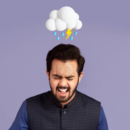 Téléchargez les photos : Désespéré jeune homme hindou triste criant souffrent de douleur, migraine avec un nuage abstrait de foudre et signe de pluie au-dessus de la tête isolé sur fond de studio violet. Mauvaise humeur, maladie et stress - en image libre de droit