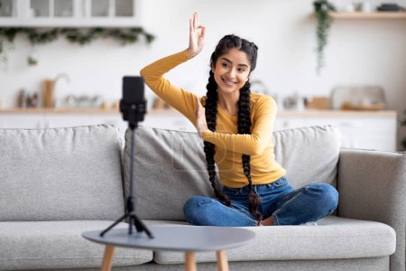 Photo for Blogging Concept. Cheerful Indian Woman Dancing At Camera, Young Eastern Female Making Bharatanatyam Hand Dance While Recording Video At Home, Hindu Lady Using Smartphone On Tripod, Free Space - Royalty Free Image