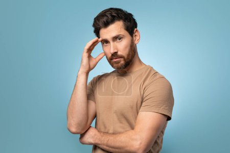 Photo for Portrait of attractive bearded middle aged man with smooth skin standing isolated over blue background and looking at camera. Male posing at studio in t-shirt - Royalty Free Image