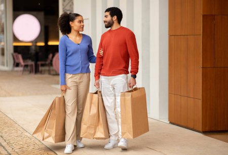 Photo for Couple Shopping. Full Length Of Multiethnic Husband And Wife Standing Holding Many Paper Shopper Bags On Weekend Posing At Modern Mall Outside. Sales And Discounts Offer Concept - Royalty Free Image