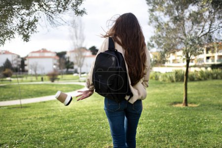 Photo for Millennial caucasian lady brunette student with backpack walking, throws out garbage on grass in park, outdoor, back. Environmental pollution, human and nature, recycling problem - Royalty Free Image