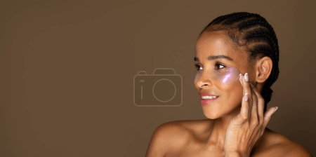 Téléchargez les photos : Portrait de femme noire d'âge moyen portant sous les bandeaux oculaires, prenant soin de sa peau, isolée sur fond brun, panorama avec espace de copie - en image libre de droit