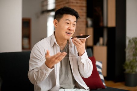 Photo for Happy asian middle aged man recording audio message on smartphone, having conversation with his friend, resting at home, copy space. Modern technologies and communication concept - Royalty Free Image