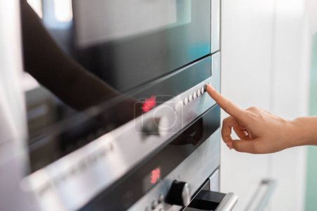 Photo for Woman Touching Control Panel On Electric Oven In Kicthen With Finger, Closeup Shot Of Unrecognizable Housewife Selecting Cooking Mode On Modern Microwave While Cooking Food At Home, Closeup Shot - Royalty Free Image
