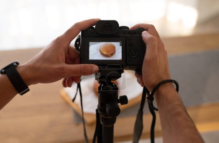Téléchargez les photos : Homme méconnaissable prenant une photo de délicieux hamburger juteux sur une table en bois, mains masculines tenant un appareil photo dslr, recadré de nourriture blogueur influenceur tir repas, espace de copie - en image libre de droit