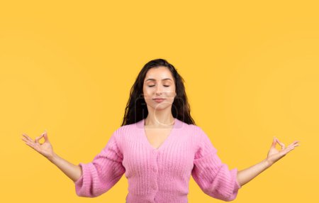 Photo for Smiling millennial middle eastern lady with closed eyes meditation, enjoy rest and relax, calm and silence isolated on yellow studio background. People emotions, break from work - Royalty Free Image