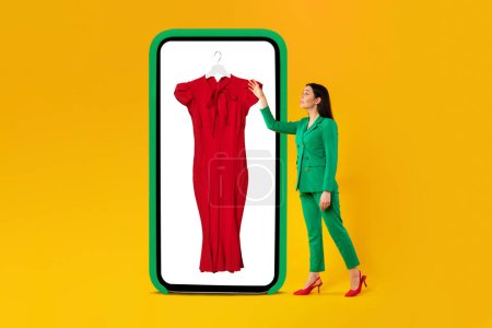 Photo for Mobile shopping. Woman choosing new dress, pointing at huge cellphone screen, buying online on yellow studio background. E-commerce concept. Collage - Royalty Free Image