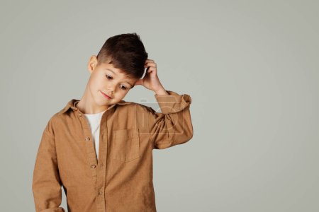 Photo for Sad pensive little kid 6 years old in casual thinks, scratching his head isolated on gray background, studio. Question, childhood, study problems, pupil emotions, ad and offer - Royalty Free Image