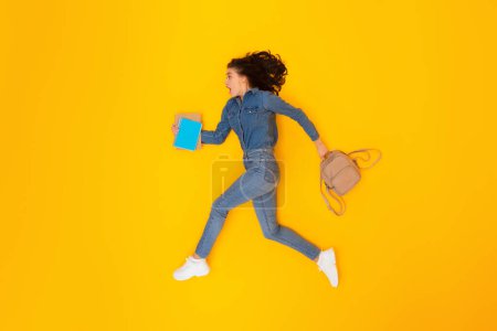 Photo for Shocked Woman Student Running In Mid Air Holding Copybooks And Backpack Looking Aside In Studio Over Yellow Background. Full Length Shot Of Female Hurrying To Learn. Educational Offer Concept - Royalty Free Image