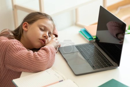 Photo for Sad tired european teenager girl doing homework, sleeping near computer with empty screen in living room interior. Overwork, problems with study, knowledge, education remotely at home - Royalty Free Image