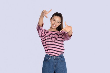Photo for Happy cheerful beautiful long-haired young hispanic woman wearing stylish casual outfit making frame with fingers and smiling, isolated on grey studio background, copy space - Royalty Free Image