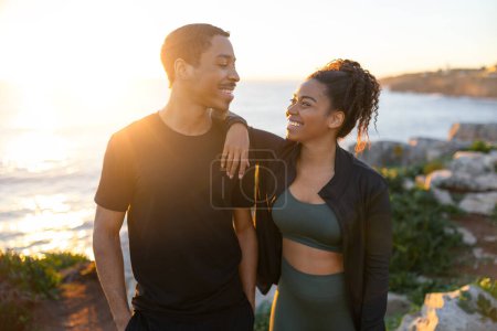 Photo for Cheerful millennial african american lady and male in sportswear enjoy active lifestyle and training on ocean beach at sunrise. Morning workout, body care together, weight loss outdoor - Royalty Free Image
