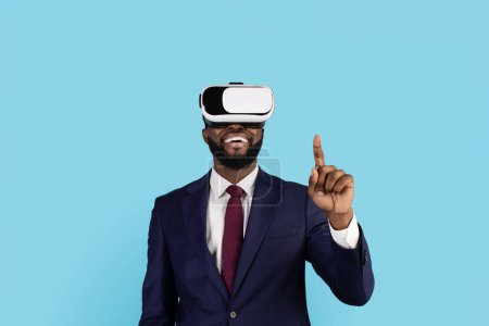 Photo for Black Businessman Using VR Glasses And Touching Air With Finger, Happy African American Male Entrepreneur Experiencing Virtual Reality, Enjoying Video Games While Standing On Blue Background - Royalty Free Image