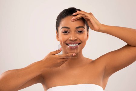 Photo for Aesthetic medicine, cosmetology, beauty injections. Cheerful smiling millennial pretty half-naked black woman touching her beautiful face, isolated on studio background, closeup - Royalty Free Image