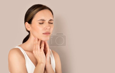 Photo for Pharyngitis, tonsillitis. Upset millennial caucasian woman in white top has painful throat when swallowing, touching her neck, isolated on beige studio background, panorama with copy space - Royalty Free Image