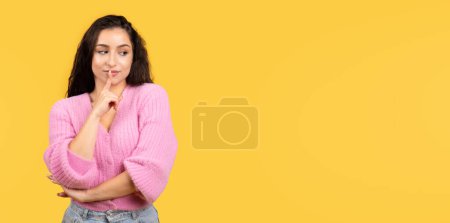 Photo for Serious pensive millennial arab lady in casual show shhh sign, presses finger to lips isolated on yellow background, studio. Secret, mystery, dream, lifestyle and surprise, ad and offer - Royalty Free Image