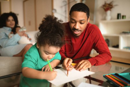 Photo for Happy african american family spending time together at home, handsome millennial black man drawing or coloring with his little son, mother relaxing on couch, feeding baby child, copy space - Royalty Free Image