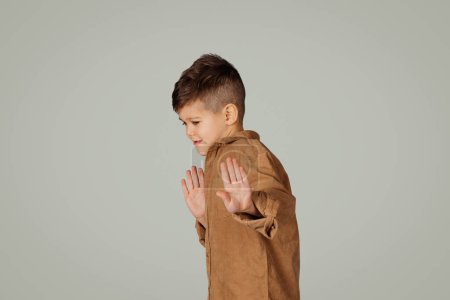 Photo for Despaired sad little child 6 years old in casual clothes makes stop gesture with hands isolated on gray background, studio. Stress, childhood, study problems, bad emotions, ad and offer - Royalty Free Image