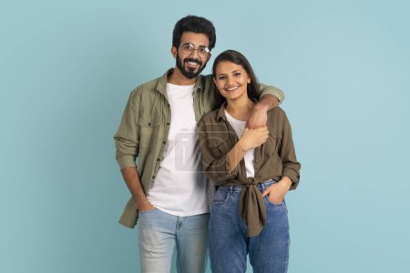 Téléchargez les photos : Portrait de joyeux heureux élégant beau jeune couple indien hipsters posant ensemble sur fond de studio coloré, embrassant et souriant à la caméra. Amour, relations, affection - en image libre de droit
