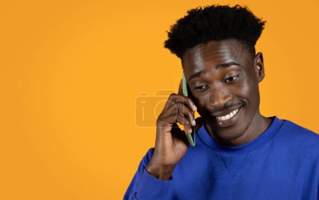 Photo for Cheerful happy handsome young black man in stylish casual outfit using smartphone over yellow studio background, have phone conversation, closeup, copy space. Communication concept - Royalty Free Image